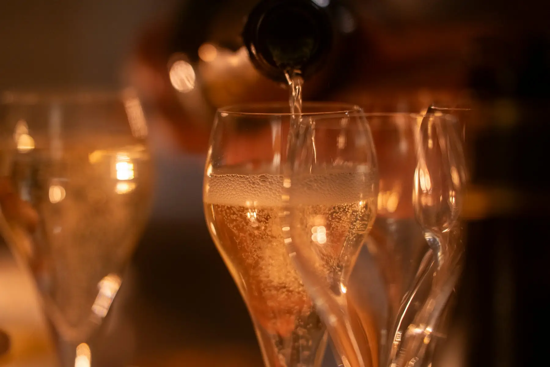 Champagne being poured into glasses in warm light